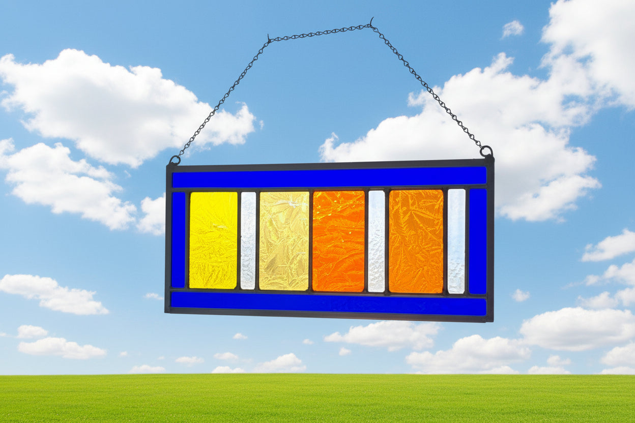Colorful glass panel with orange, yellow, and blue squares in front of a window with blinds.