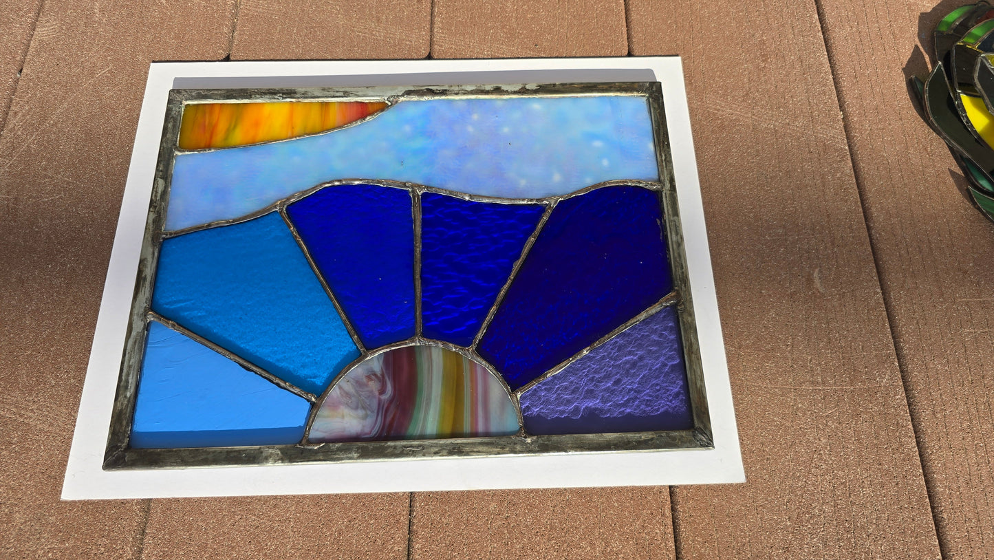 Stained glass panel with blue and multicolored design on a cardboard background